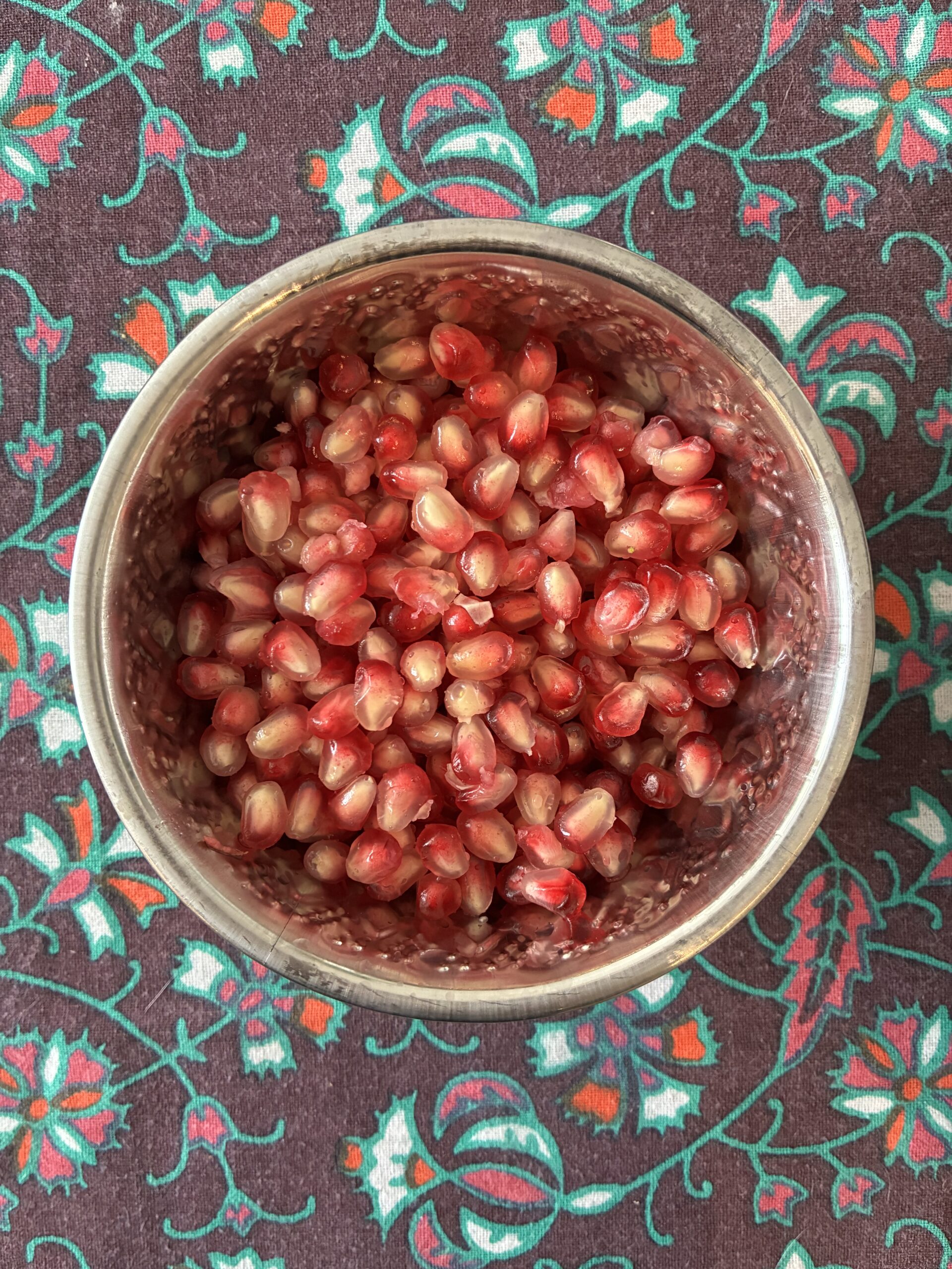 Bowl of pomegranate seeds on a colourful tablecloth