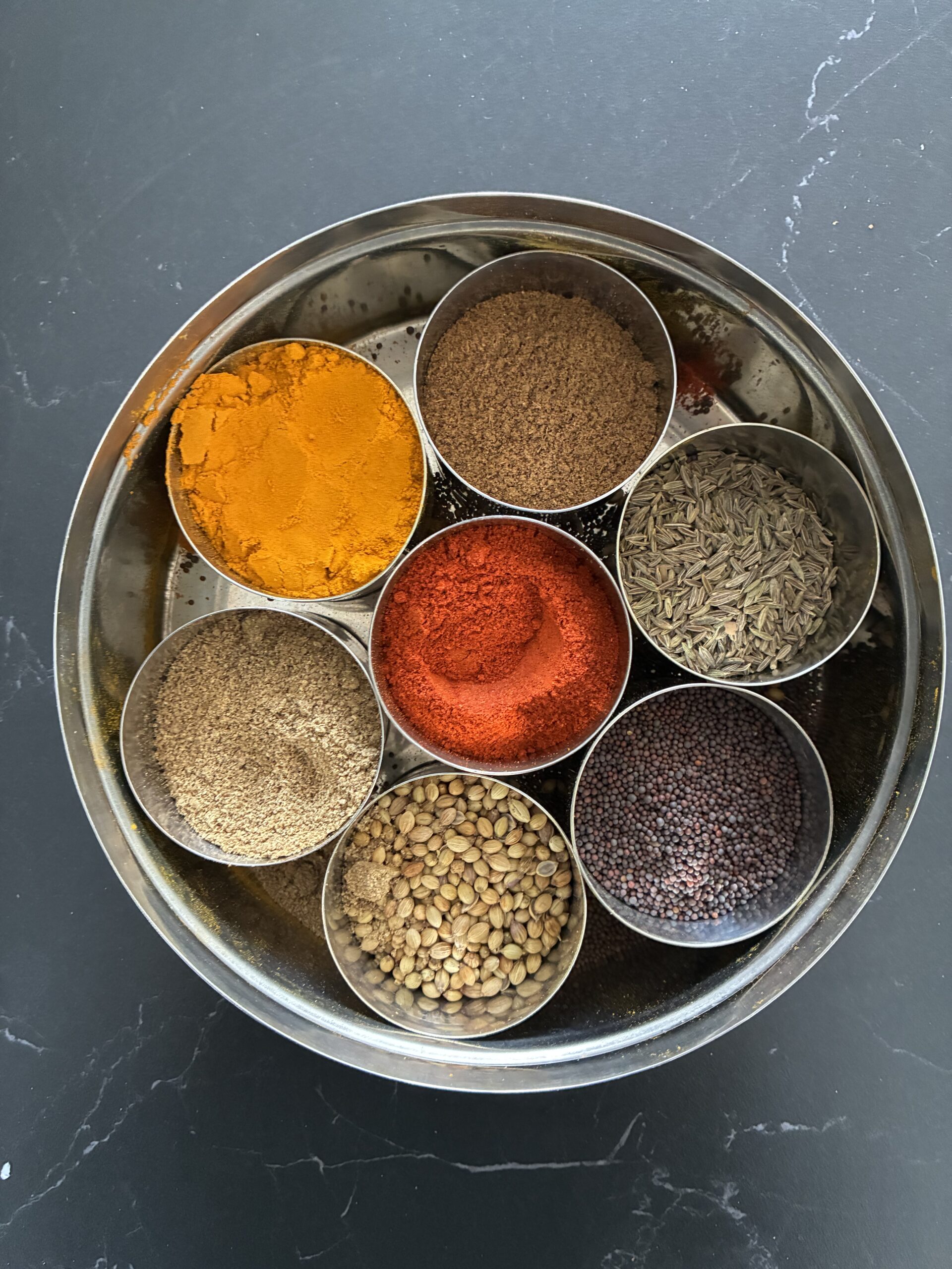 Traditional Indian round spice tin containing seven spices